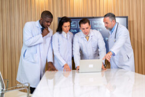 A Group Of Doctors Looks At Laptop Computer Brainstorming Meeting While Listening To Medical Report - Contador em Goiás | Contec Contabilidade